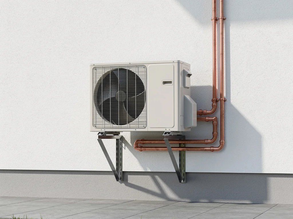 Groupe extérieur air/eau posé au pied d'une maison en crépi clair