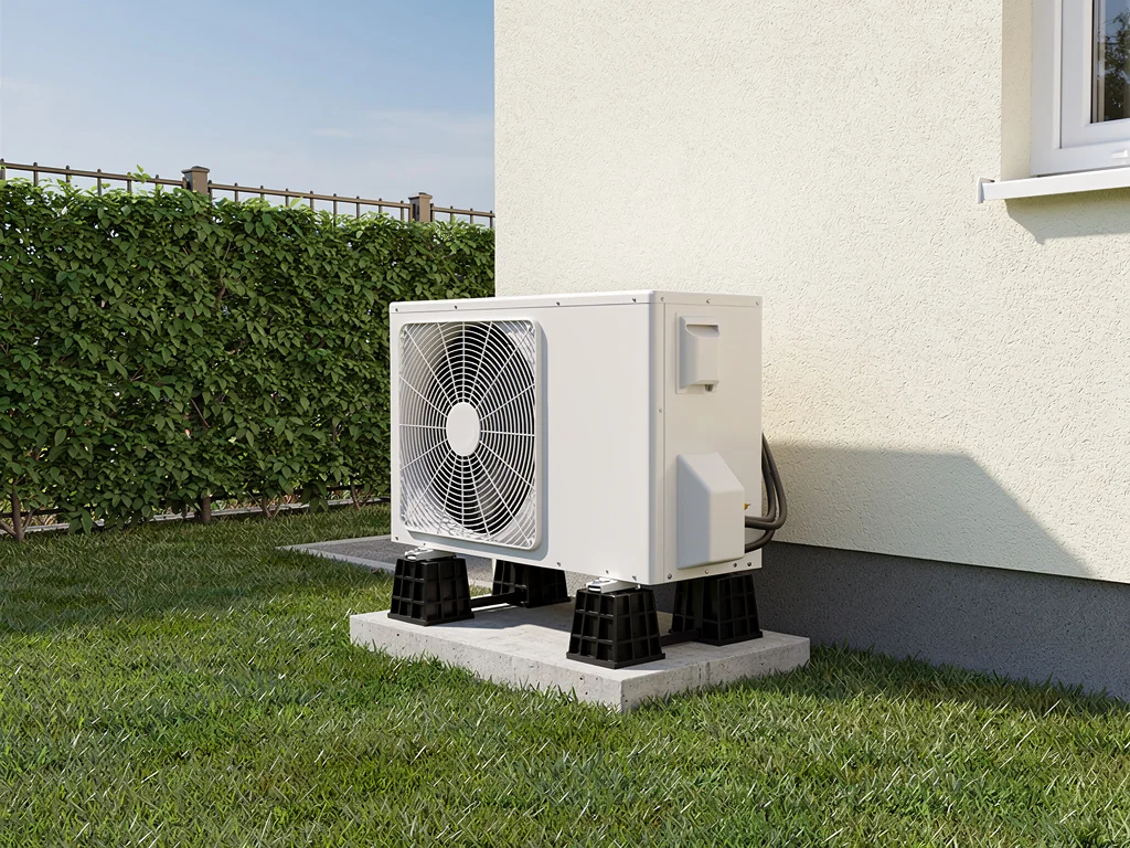 Pompe à chaleur air/eau installée sur plots dans un jardin clôturé